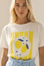 Βαμβακερό Κοντομάνικο T-Shirt Amalfi Limone Περιγραφή Προϊόντος Το βαμβακερό κοντομάνικο T-Shirt “Amalfi Limone” αποπνέει καλοκαιρινή φρεσκάδα και ιταλικό αέρα. Η εντυπωσιακή lemon στάμπα σε φωτεινές κίτρινες αποχρώσεις χαρίζει playful και κομψό χαρακτήρα, ιδανικό για ανοιξιάτικα και καλοκαιρινά outfits. Η γραμμή του είναι άνετη και χαλαρή, καλύπτει έως Large και εφαρμόζει όμορφα χωρίς να πιέζει. Το μαλακό βαμβακερό ύφασμα με ελαστικότητα προσφέρει άνεση και φυσική εφαρμογή καθ’ όλη τη διάρκεια της ημέρας. Styling Tip Συνδύασέ το με τη γαλάζια ψηλόμεση παντελόνα wide leg για ένα φωτεινό, ισορροπημένο και κομψό καλοκαιρινό look. Εναλλακτικά, φόρεσέ το με denim shorts για πιο casual αποτέλεσμα ή με λευκό παντελόνι για καθαρό, resort-inspired outfit.