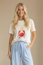 Βαμβακερό Κοντομάνικο T-Shirt “La Dolce Vita” Το βαμβακερό κοντομάνικο T-shirt “La Dolce Vita” είναι η ιδανική επιλογή για casual και καλοκαιρινά looks με ιταλικό αέρα. Διαθέτει εντυπωσιακή στάμπα με crab print και lettering, που δίνει playful και fresh χαρακτήρα στο outfit. Η γραμμή του είναι άνετη και χαλαρή, καλύπτοντας έως Large, ενώ το μαλακό βαμβακερό ύφασμα με ελαστικότητα προσφέρει άνεση και ευχάριστη αίσθηση όλη την ημέρα. Ιδανικό για καθημερινές εμφανίσεις, ταξίδια και city looks. Styling Tip Συνδύασέ το με ψηλόμεση παντελόνα ή denim shorts για relaxed καλοκαιρινό look. Με λινή παντελόνα και sneakers αποκτά πιο chic casual χαρακτήρα, ενώ με σακάκι γίνεται ιδανικό για smart everyday εμφανίσεις.