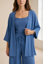 Σετ Κιμονό Παντελόνα Crepe in Indigo Το Σετ Κιμονό Παντελόνα Crepe in Indigo είναι η επιτομή του effortless elegance. Ένα αέρινο co-ord set με minimal αισθητική που συνδυάζει άνεση, κομψότητα και relaxed πολυτέλεια για όλες τις ώρες της ημέρας. Το kimono με τα φαρδιά 3/4 μανίκια και τη loose γραμμή αγκαλιάζει όμορφα το σώμα, ενώ η wide leg παντελόνα με λάστιχο και κορδόνι στη μέση προσφέρει άνετη εφαρμογή χωρίς να πιέζει. Η ανάλαφρη crêpe σύνθεση χαρίζει δροσερή αίσθηση και elegant κίνηση σε κάθε βήμα. Ιδανικό για resort looks, city chic εμφανίσεις αλλά και effortless occasion outfits με minimal αισθητική. Styling Tip Συνδύασέ το με flat sandals και minimal χρυσά κοσμήματα για chic resort εμφάνιση ή με mules και structured τσάντα για elevated city look