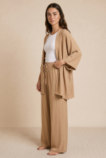 Σετ Κιμονό Παντελόνα Crepe in Camel Το Σετ Κιμονό Παντελόνα Crepe in Camel είναι η επιτομή του effortless elegance. Ένα αέρινο co-ord set με minimal αισθητική που συνδυάζει άνεση, κομψότητα και relaxed πολυτέλεια για όλες τις ώρες της ημέρας. Το kimono με τα φαρδιά 3/4 μανίκια και τη loose γραμμή αγκαλιάζει όμορφα το σώμα, ενώ η wide leg παντελόνα με λάστιχο και κορδόνι στη μέση προσφέρει άνετη εφαρμογή χωρίς να πιέζει. Η ανάλαφρη crêpe σύνθεση χαρίζει δροσερή αίσθηση και elegant κίνηση σε κάθε βήμα. Ιδανικό για resort looks, city chic εμφανίσεις αλλά και effortless occasion outfits με minimal αισθητική. Styling Tip Συνδύασέ το με flat sandals και minimal χρυσά κοσμήματα για chic resort εμφάνιση ή με mules και structured τσάντα για elevated city look