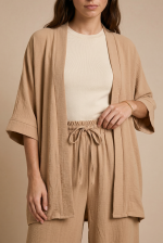 Σετ Κιμονό Παντελόνα Crepe in Camel Το Σετ Κιμονό Παντελόνα Crepe in Camel είναι η επιτομή του effortless elegance. Ένα αέρινο co-ord set με minimal αισθητική που συνδυάζει άνεση, κομψότητα και relaxed πολυτέλεια για όλες τις ώρες της ημέρας. Το kimono με τα φαρδιά 3/4 μανίκια και τη loose γραμμή αγκαλιάζει όμορφα το σώμα, ενώ η wide leg παντελόνα με λάστιχο και κορδόνι στη μέση προσφέρει άνετη εφαρμογή χωρίς να πιέζει. Η ανάλαφρη crêpe σύνθεση χαρίζει δροσερή αίσθηση και elegant κίνηση σε κάθε βήμα. Ιδανικό για resort looks, city chic εμφανίσεις αλλά και effortless occasion outfits με minimal αισθητική. Styling Tip Συνδύασέ το με flat sandals και minimal χρυσά κοσμήματα για chic resort εμφάνιση ή με mules και structured τσάντα για elevated city look