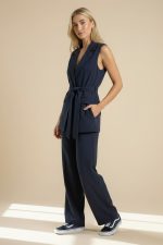 Navy Σετ Γιλέκο και Παντελόνι Minimal, κομψό και effortlessly chic, το Navy Σετ Γιλέκο και Παντελόνι είναι το απόλυτο co-ord set για all day εμφανίσεις με elevated αισθητική. Το αμάνικο tailored γιλέκο με ζώνη στη μέση δημιουργεί κομψή σιλουέτα και συνδυάζεται τέλεια με το άνετο ίσιο παντελόνι, προσφέροντας sophisticated look χωρίς να χάνει σε άνεση. Το ύφασμά του έχει μαλακή αίσθηση, στρώνει υπέροχα στο σώμα και είναι ιδανικό τόσο για office looks όσο και για πιο stylish καθημερινές εμφανίσεις.  Styling Tip Συνδύασέ το με λευκό rib top ή σατινέ lingerie top από τη συλλογή μας για elegant minimal looks από το πρωί μέχρι το βράδυ.