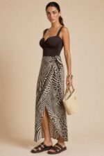 Penelope Viscose Wrap Midi Skirt in brown Κωδικός: 3034 Χαρακτηριστικά Προϊόντος • Πολυμορφική κρουαζέ midi φούστα • Εσωτερικό φύλλο που ασφαλίζει με κορδονάκι • Εξωτερικό φύλλο που τυλίγει το σώμα και δένει στη μέση • Ρυθμιζόμενη εφαρμογή που προσαρμόζεται εύκολα στη σιλουέτα • Άνετη γραμμή με φυσική κίνηση • Midi μήκος • Ασύμμετρο τελείωμα • One Size – καλύπτει έως X-Large • Viscose blend σύνθεση καφέ-μπλέ  αποχρωση • Ανάλαφρη, δροσερή και breathable αίσθηση • Πολύ μαλακή υφή με όμορφη εφαρμογή Διαστάσεις (One Size) • Μέση: έως 105 cm (ρυθμιζόμενη με δέσιμο) • Περιφέρεια: έως 120 cm • Μήκος: Midi Asymmetrical Οδηγίες Φροντίδας • Πλύσιμο στους 30°C • Χωρίς στύψιμο • Σιδέρωμα σε χαμηλή θερμοκρασία