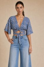 Iris Viscose Κρουαζέ Top in blue Χαρακτηριστικά Προϊόντος Πολυμορφικό κρουαζέ / wrap σχέδιο Δένει μπροστά ή πίσω Μπορεί να φορεθεί και ανάποδα Άνοιγμα μπροστά ή στην πλάτη, ανάλογα με το styling Άνετη γραμμή μανικιού ,μήκος κλασσικού κοντομάνικου Ασύμμετρο τελείωμα Άνετη, προσαρμοζόμενη εφαρμογή Πολύ μαλακό και δροσερό ύφασμα Ανάλαφρη & breathable αίσθηση Viscose Σημείωση για ευαίσθητα δέρματα: Η viscose έχει απαλή και λεία αίσθηση και μπορεί να αποτελεί άνετη επιλογή για άτομα που ενοχλούνται από πιο τραχιές υφές. Η ατομική ευαισθησία ή αλλεργία, ωστόσο, διαφέρει από άτομο σε άτομο. Διαστάσεις Μέγεθος Στήθος Μέση Μήκος One Size έως 100 cm Ρυθμιζόμενη με το δέσιμο Κανονικό crop Φροντίδα Πλύσιμο έως 30°C Χωρίς στύψιμο Σιδέρωμα σε κανονική θερμοκρασία