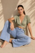 Iris Viscose Κρουαζέ Top in green Χαρακτηριστικά Προϊόντος Πολυμορφικό κρουαζέ / wrap σχέδιο Δένει μπροστά ή πίσω Μπορεί να φορεθεί και ανάποδα Άνοιγμα μπροστά ή στην πλάτη, ανάλογα με το styling Άνετη γραμμή μανικιού ,μήκος κλασσικού κοντομάνικου Ασύμμετρο τελείωμα Άνετη, προσαρμοζόμενη εφαρμογή Πολύ μαλακό και δροσερό ύφασμα Ανάλαφρη & breathable αίσθηση Viscose Σημείωση για ευαίσθητα δέρματα: Η viscose έχει απαλή και λεία αίσθηση και μπορεί να αποτελεί άνετη επιλογή για άτομα που ενοχλούνται από πιο τραχιές υφές. Η ατομική ευαισθησία ή αλλεργία, ωστόσο, διαφέρει από άτομο σε άτομο. Διαστάσεις Μέγεθος Στήθος Μέση Μήκος One Size έως 100 cm Ρυθμιζόμενη με το δέσιμο Κανονικό crop Φροντίδα Πλύσιμο έως 30°C Χωρίς στύψιμο Σιδέρωμα σε κανονική θερμοκρασία
