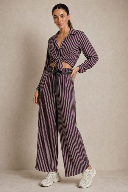 Ριγέ satin-effect Σετ  purple Χαρακτηριστικά Πουκάμισο 100% Viscose με satin-effect επεξεργασία Κλασικός γιακάς Κουμπιά μπροστά Μακρύ μανίκι Κανονικό μήκος Κανονική προς άνετη γραμμή Μπορεί να δεθεί μπροστά Πολύ απαλή & δροσερή αίσθηση Παντελόνα 100% Viscose με satin-effect επεξεργασία Wide-leg γραμμή Λάστιχο στη μέση μπροστά και πίσω Πλαϊνές τσέπες Άνετη, ρευστή εφαρμογή Διαστάσεις Πουκάμισο Στήθος: έως 112 cm Περιφέρεια: έως 116 cm Μήκος: 66 cm Παντελόνα Μέση: ελαστική, έως 96 cm Περιφέρεια: έως 116 cm Μήκος: 108 cm Φροντίδα Πλύσιμο σε κρύο νερό Χωρίς στύψιμο Χαμηλές στροφές Όχι στεγνωτήριο Στέγνωμα φυσικά, χωρίς άμεση έκθεση στον ήλιο Non-iron – δεν απαιτεί σιδέρωμα Αίσθηση υφάσματος Το ύφασμα είναι εξαιρετικά μαλακό, ελαφρύ και δροσερό στην επαφή με το σώμα, χωρίς τραχιά αίσθηση. Η απαλή viscose το καθιστά μια ιδιαίτερα άνετη επιλογή και για ευαίσθητες επιδερμίδες. Σε περίπτωση γνωστής αλλεργίας ή ιδιαίτερης δερματικής ευαισθησίας, συνιστάται πάντα να λαμβάνεται υπόψη η ατομική αντίδραση στα υφάσματα.