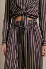 Ριγέ satin-effect Σετ  purple Χαρακτηριστικά Πουκάμισο 100% Viscose με satin-effect επεξεργασία Κλασικός γιακάς Κουμπιά μπροστά Μακρύ μανίκι Κανονικό μήκος Κανονική προς άνετη γραμμή Μπορεί να δεθεί μπροστά Πολύ απαλή & δροσερή αίσθηση Παντελόνα 100% Viscose με satin-effect επεξεργασία Wide-leg γραμμή Λάστιχο στη μέση μπροστά και πίσω Πλαϊνές τσέπες Άνετη, ρευστή εφαρμογή Διαστάσεις Πουκάμισο Στήθος: έως 112 cm Περιφέρεια: έως 116 cm Μήκος: 66 cm Παντελόνα Μέση: ελαστική, έως 96 cm Περιφέρεια: έως 116 cm Μήκος: 108 cm Φροντίδα Πλύσιμο σε κρύο νερό Χωρίς στύψιμο Χαμηλές στροφές Όχι στεγνωτήριο Στέγνωμα φυσικά, χωρίς άμεση έκθεση στον ήλιο Non-iron – δεν απαιτεί σιδέρωμα Αίσθηση υφάσματος Το ύφασμα είναι εξαιρετικά μαλακό, ελαφρύ και δροσερό στην επαφή με το σώμα, χωρίς τραχιά αίσθηση. Η απαλή viscose το καθιστά μια ιδιαίτερα άνετη επιλογή και για ευαίσθητες επιδερμίδες. Σε περίπτωση γνωστής αλλεργίας ή ιδιαίτερης δερματικής ευαισθησίας, συνιστάται πάντα να λαμβάνεται υπόψη η ατομική αντίδραση στα υφάσματα.