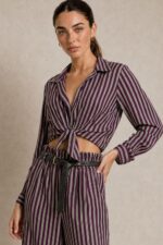 Ριγέ satin-effect Σετ  purple Χαρακτηριστικά Πουκάμισο 100% Viscose με satin-effect επεξεργασία Κλασικός γιακάς Κουμπιά μπροστά Μακρύ μανίκι Κανονικό μήκος Κανονική προς άνετη γραμμή Μπορεί να δεθεί μπροστά Πολύ απαλή & δροσερή αίσθηση Παντελόνα 100% Viscose με satin-effect επεξεργασία Wide-leg γραμμή Λάστιχο στη μέση μπροστά και πίσω Πλαϊνές τσέπες Άνετη, ρευστή εφαρμογή Διαστάσεις Πουκάμισο Στήθος: έως 112 cm Περιφέρεια: έως 116 cm Μήκος: 66 cm Παντελόνα Μέση: ελαστική, έως 96 cm Περιφέρεια: έως 116 cm Μήκος: 108 cm Φροντίδα Πλύσιμο σε κρύο νερό Χωρίς στύψιμο Χαμηλές στροφές Όχι στεγνωτήριο Στέγνωμα φυσικά, χωρίς άμεση έκθεση στον ήλιο Non-iron – δεν απαιτεί σιδέρωμα Αίσθηση υφάσματος Το ύφασμα είναι εξαιρετικά μαλακό, ελαφρύ και δροσερό στην επαφή με το σώμα, χωρίς τραχιά αίσθηση. Η απαλή viscose το καθιστά μια ιδιαίτερα άνετη επιλογή και για ευαίσθητες επιδερμίδες. Σε περίπτωση γνωστής αλλεργίας ή ιδιαίτερης δερματικής ευαισθησίας, συνιστάται πάντα να λαμβάνεται υπόψη η ατομική αντίδραση στα υφάσματα.
