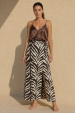 Victoria Viscose Wrap Midi Skirt Κωδικός: 3034 Χαρακτηριστικά Προϊόντος • Πολυμορφική κρουαζέ midi φούστα • Εσωτερικό φύλλο που ασφαλίζει με κορδονάκι • Εξωτερικό φύλλο που τυλίγει το σώμα και δένει στη μέση • Ρυθμιζόμενη εφαρμογή που προσαρμόζεται εύκολα στη σιλουέτα • Άνετη γραμμή με φυσική κίνηση • Midi μήκος • Ασύμμετρο τελείωμα • One Size – καλύπτει έως Large • Viscose blend σύνθεση καφέ-μαύρο απόχρωση • Ανάλαφρη, δροσερή και breathable αίσθηση • Πολύ μαλακή υφή με όμορφη εφαρμογή Διαστάσεις (One Size) • Μέση: έως86 cm (ρυθμιζόμενη με δέσιμο) • Περιφέρεια: έως 105 cm • Μήκος: Midi Asymmetrical Οδηγίες Φροντίδας • Πλύσιμο στους 30°C • Χωρίς στύψιμο • Σιδέρωμα σε χαμηλή θερμοκρασία