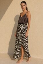Victoria Viscose Wrap Midi Skirt Κωδικός: 3034 Χαρακτηριστικά Προϊόντος • Πολυμορφική κρουαζέ midi φούστα • Εσωτερικό φύλλο που ασφαλίζει με κορδονάκι • Εξωτερικό φύλλο που τυλίγει το σώμα και δένει στη μέση • Ρυθμιζόμενη εφαρμογή που προσαρμόζεται εύκολα στη σιλουέτα • Άνετη γραμμή με φυσική κίνηση • Midi μήκος • Ασύμμετρο τελείωμα • One Size – καλύπτει έως Large • Viscose blend σύνθεση καφέ-μαύρο απόχρωση • Ανάλαφρη, δροσερή και breathable αίσθηση • Πολύ μαλακή υφή με όμορφη εφαρμογή Διαστάσεις (One Size) • Μέση: έως86 cm (ρυθμιζόμενη με δέσιμο) • Περιφέρεια: έως 105 cm • Μήκος: Midi Asymmetrical Οδηγίες Φροντίδας • Πλύσιμο στους 30°C • Χωρίς στύψιμο • Σιδέρωμα σε χαμηλή θερμοκρασία
