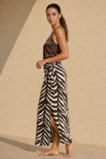 Victoria Viscose Wrap Midi Skirt Κωδικός: 3034 Χαρακτηριστικά Προϊόντος • Πολυμορφική κρουαζέ midi φούστα • Εσωτερικό φύλλο που ασφαλίζει με κορδονάκι • Εξωτερικό φύλλο που τυλίγει το σώμα και δένει στη μέση • Ρυθμιζόμενη εφαρμογή που προσαρμόζεται εύκολα στη σιλουέτα • Άνετη γραμμή με φυσική κίνηση • Midi μήκος • Ασύμμετρο τελείωμα • One Size – καλύπτει έως Large • Viscose blend σύνθεση καφέ-μαύρο απόχρωση • Ανάλαφρη, δροσερή και breathable αίσθηση • Πολύ μαλακή υφή με όμορφη εφαρμογή Διαστάσεις (One Size) • Μέση: έως86 cm (ρυθμιζόμενη με δέσιμο) • Περιφέρεια: έως 105 cm • Μήκος: Midi Asymmetrical Οδηγίες Φροντίδας • Πλύσιμο στους 30°C • Χωρίς στύψιμο • Σιδέρωμα σε χαμηλή θερμοκρασία