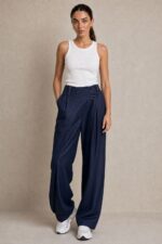Viscose Denim Wrap Wide Leg Pants Χαρακτηριστικά Ύφασμα: Viscose με denim effect Υφή: Πολύ μαλακή και απαλή Αίσθηση: Ελαστική και άνετη Γραμμή: Wide leg Μέση: Ιδιαίτερη λοξή / asymmetric wrap μέση Λάστιχο στη μέση για μεγαλύτερη άνεση Λεπτομέρεια: Διακοσμητικό κουμπί στο μπροστινό μέρος Τσέπες: Πλαϊνές Εφαρμογή: Άνετη, με ρευστό πέσιμο Μέγεθος: One Size Καλύπτει έως Large Sensitive Skin Friendly Η απαλή viscose και η μαλακή αίσθηση του υφάσματος την καθιστούν κατάλληλη επιλογή για όσους προτιμούν μαλακά υφάσματα ή έχουν ευαίσθητο δέρμα. Σε αντίθεση με ένα πιο άκαμπτο denim, έχει πιο ήπια και ευχάριστη επαφή με το σώμα. Φροντίδα Πλύσιμο έως 30°C, σε χαμηλές στροφές. Αποφύγετε το έντονο στύψιμο. Εάν χρειαστεί σιδέρωμα, χρησιμοποιήστε χαμηλή θερμοκρασία. Προτείνεται φυσικό στέγνωμα και αποφυγή πολύωρης άμεσης έκθεσης στον ήλιο, ώστε να διατηρηθεί καλύτερα η απόχρωση και η υφή του υφάσματος.