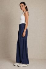 Viscose Denim Wrap Wide Leg Pants Χαρακτηριστικά Ύφασμα: Viscose με denim effect Υφή: Πολύ μαλακή και απαλή Αίσθηση: Ελαστική και άνετη Γραμμή: Wide leg Μέση: Ιδιαίτερη λοξή / asymmetric wrap μέση Λάστιχο στη μέση για μεγαλύτερη άνεση Λεπτομέρεια: Διακοσμητικό κουμπί στο μπροστινό μέρος Τσέπες: Πλαϊνές Εφαρμογή: Άνετη, με ρευστό πέσιμο Μέγεθος: One Size Καλύπτει έως Large Sensitive Skin Friendly Η απαλή viscose και η μαλακή αίσθηση του υφάσματος την καθιστούν κατάλληλη επιλογή για όσους προτιμούν μαλακά υφάσματα ή έχουν ευαίσθητο δέρμα. Σε αντίθεση με ένα πιο άκαμπτο denim, έχει πιο ήπια και ευχάριστη επαφή με το σώμα. Φροντίδα Πλύσιμο έως 30°C, σε χαμηλές στροφές. Αποφύγετε το έντονο στύψιμο. Εάν χρειαστεί σιδέρωμα, χρησιμοποιήστε χαμηλή θερμοκρασία. Προτείνεται φυσικό στέγνωμα και αποφυγή πολύωρης άμεσης έκθεσης στον ήλιο, ώστε να διατηρηθεί καλύτερα η απόχρωση και η υφή του υφάσματος.