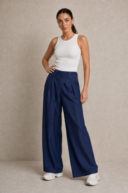 Viscose Denim Wrap Wide Leg Pants Χαρακτηριστικά Ύφασμα: Viscose με denim effect Υφή: Πολύ μαλακή και απαλή Αίσθηση: Ελαστική και άνετη Γραμμή: Wide leg Μέση: Ιδιαίτερη λοξή / asymmetric wrap μέση Λάστιχο στη μέση για μεγαλύτερη άνεση Λεπτομέρεια: Διακοσμητικό κουμπί στο μπροστινό μέρος Τσέπες: Πλαϊνές Εφαρμογή: Άνετη, με ρευστό πέσιμο Μέγεθος: One Size Καλύπτει έως Large Sensitive Skin Friendly Η απαλή viscose και η μαλακή αίσθηση του υφάσματος την καθιστούν κατάλληλη επιλογή για όσους προτιμούν μαλακά υφάσματα ή έχουν ευαίσθητο δέρμα. Σε αντίθεση με ένα πιο άκαμπτο denim, έχει πιο ήπια και ευχάριστη επαφή με το σώμα. Φροντίδα Πλύσιμο έως 30°C, σε χαμηλές στροφές. Αποφύγετε το έντονο στύψιμο. Εάν χρειαστεί σιδέρωμα, χρησιμοποιήστε χαμηλή θερμοκρασία. Προτείνεται φυσικό στέγνωμα και αποφυγή πολύωρης άμεσης έκθεσης στον ήλιο, ώστε να διατηρηθεί καλύτερα η απόχρωση και η υφή του υφάσματος.