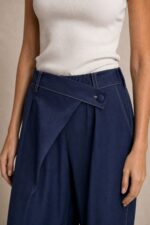 Viscose Denim Wrap Wide Leg Pants Χαρακτηριστικά Ύφασμα: Viscose με denim effect Υφή: Πολύ μαλακή και απαλή Αίσθηση: Ελαστική και άνετη Γραμμή: Wide leg Μέση: Ιδιαίτερη λοξή / asymmetric wrap μέση Λάστιχο στη μέση για μεγαλύτερη άνεση Λεπτομέρεια: Διακοσμητικό κουμπί στο μπροστινό μέρος Τσέπες: Πλαϊνές Εφαρμογή: Άνετη, με ρευστό πέσιμο Μέγεθος: One Size Καλύπτει έως Large Sensitive Skin Friendly Η απαλή viscose και η μαλακή αίσθηση του υφάσματος την καθιστούν κατάλληλη επιλογή για όσους προτιμούν μαλακά υφάσματα ή έχουν ευαίσθητο δέρμα. Σε αντίθεση με ένα πιο άκαμπτο denim, έχει πιο ήπια και ευχάριστη επαφή με το σώμα. Φροντίδα Πλύσιμο έως 30°C, σε χαμηλές στροφές. Αποφύγετε το έντονο στύψιμο. Εάν χρειαστεί σιδέρωμα, χρησιμοποιήστε χαμηλή θερμοκρασία. Προτείνεται φυσικό στέγνωμα και αποφυγή πολύωρης άμεσης έκθεσης στον ήλιο, ώστε να διατηρηθεί καλύτερα η απόχρωση και η υφή του υφάσματος.