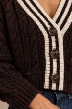 GNT Cable Knit Cardigan in Brown Χαρακτηριστικά Προϊόντος • Ύφασμα: Μαλακό πλεκτό • Ανάγλυφη cable knit / πλεξούδα ύφανση • V λαιμόκοψη • Contrast πλεκτή λεπτομέρεια περιμετρικά • Κλείσιμο μπροστά με κουμπιά • Μακριά μανίκια • Rib τελείωμα σε μανίκια και κάτω μέρος • Κανονική γραμμή • Κανονικό προς ελαφρώς cropped μήκος • Μαλακή και άνετη αίσθηση • One Size – καλύπτει έως Large Οδηγίες Φροντίδας • Πλύσιμο σε κρύο νερό • Στύψιμο μόνο σε χαμηλές στροφές • Στέγνωμα οριζόντια πάνω στην απλώστρα, ώστε να διατηρεί τη φόρμα του πλεκτού • Αποφύγετε το στεγνωτήριο και την άμεση επαφή με πηγές θερμότητας