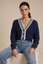 GNT Cable Knit Cardigan in Burgundy Χαρακτηριστικά Προϊόντος • Ύφασμα: Μαλακό πλεκτό • Ανάγλυφη cable knit / πλεξούδα ύφανση • V λαιμόκοψη • Contrast πλεκτή λεπτομέρεια περιμετρικά • Κλείσιμο μπροστά με κουμπιά • Μακριά μανίκια • Rib τελείωμα σε μανίκια και κάτω μέρος • Κανονική γραμμή • Κανονικό προς ελαφρώς cropped μήκος • Μαλακή και άνετη αίσθηση • One Size – καλύπτει έως Large Οδηγίες Φροντίδας • Πλύσιμο σε κρύο νερό • Στύψιμο μόνο σε χαμηλές στροφές • Στέγνωμα οριζόντια πάνω στην απλώστρα, ώστε να διατηρεί τη φόρμα του πλεκτού • Αποφύγετε το στεγνωτήριο και την άμεση επαφή με πηγές θερμότητας