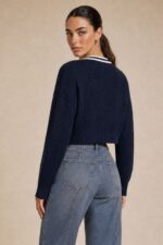 GNT Cable Knit Cardigan in Burgundy Χαρακτηριστικά Προϊόντος • Ύφασμα: Μαλακό πλεκτό • Ανάγλυφη cable knit / πλεξούδα ύφανση • V λαιμόκοψη • Contrast πλεκτή λεπτομέρεια περιμετρικά • Κλείσιμο μπροστά με κουμπιά • Μακριά μανίκια • Rib τελείωμα σε μανίκια και κάτω μέρος • Κανονική γραμμή • Κανονικό προς ελαφρώς cropped μήκος • Μαλακή και άνετη αίσθηση • One Size – καλύπτει έως Large Οδηγίες Φροντίδας • Πλύσιμο σε κρύο νερό • Στύψιμο μόνο σε χαμηλές στροφές • Στέγνωμα οριζόντια πάνω στην απλώστρα, ώστε να διατηρεί τη φόρμα του πλεκτού • Αποφύγετε το στεγνωτήριο και την άμεση επαφή με πηγές θερμότητας