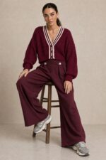GNT Cable Knit Cardigan in Burgundy Χαρακτηριστικά Προϊόντος • Ύφασμα: Μαλακό πλεκτό • Ανάγλυφη cable knit / πλεξούδα ύφανση • V λαιμόκοψη • Contrast πλεκτή λεπτομέρεια περιμετρικά • Κλείσιμο μπροστά με κουμπιά • Μακριά μανίκια • Rib τελείωμα σε μανίκια και κάτω μέρος • Κανονική γραμμή • Κανονικό προς ελαφρώς cropped μήκος • Μαλακή και άνετη αίσθηση • One Size – καλύπτει έως Large Οδηγίες Φροντίδας • Πλύσιμο σε κρύο νερό • Στύψιμο μόνο σε χαμηλές στροφές • Στέγνωμα οριζόντια πάνω στην απλώστρα, ώστε να διατηρεί τη φόρμα του πλεκτού • Αποφύγετε το στεγνωτήριο και την άμεση επαφή με πηγές θερμότητας