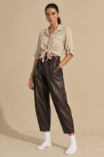 Παντελόνι Δερματίνη in Brown Κωδ:1610126 Χαρακτηριστικά Προϊόντος Ύφασμα: Μαλακή, λεία δερματίνη (leather effect) Φινίρισμα: Matte  Γραμμή: Άνετη, κανονική προς φαρδιά Barrel-inspired σχεδιασμός με χαλαρή σιλουέτα Κανονικό μήκος Άνετο μπατζάκι με ελαφρώς στρογγυλεμένη γραμμή Λάστιχο στο πίσω μέρος της μέσης για μεγαλύτερη άνεση Πρακτικές πλαϊνές τσέπες Κάθετες διακοσμητικές ραφές Μαλακή υφή και άνετη αίσθηση Οδηγίες Φροντίδας Πλύσιμο στους 30°C ή σε κρύο νερό, σε πρόγραμμα για ευαίσθητα. Χωρίς στύψιμο, για την προστασία της δερματίνης. Όχι στεγνωτήριο. Φυσικό στέγνωμα στη σκιά, μακριά από άμεση ηλιακή ακτινοβολία. Όχι σιδέρωμα. Μακριά από καλοριφέρ και άμεσες πηγές θερμότητας.