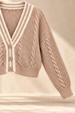 GNT Cable Knit Cardigan in Dusty Pink Χαρακτηριστικά Προϊόντος • Ύφασμα: Μαλακό πλεκτό • Ανάγλυφη cable knit / πλεξούδα ύφανση • V λαιμόκοψη • Contrast πλεκτή λεπτομέρεια περιμετρικά • Κλείσιμο μπροστά με κουμπιά • Μακριά μανίκια • Rib τελείωμα σε μανίκια και κάτω μέρος • Κανονική γραμμή • Κανονικό προς ελαφρώς cropped μήκος • Μαλακή και άνετη αίσθηση • One Size – καλύπτει έως Large Οδηγίες Φροντίδας • Πλύσιμο σε κρύο νερό • Στύψιμο μόνο σε χαμηλές στροφές • Στέγνωμα οριζόντια πάνω στην απλώστρα, ώστε να διατηρεί τη φόρμα του πλεκτού • Αποφύγετε το στεγνωτήριο και την άμεση επαφή με πηγές θερμότητας