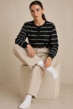 Striped Sugar Sweater in black – Ριγέ Πλεκτή Μπλούζα με Κουμπιά Κωδ:211026 Χαρακτηριστικά Προϊόντος Σύνθεση: Viscose – Modal Mix Ύφασμα: Λεπτό, εξαιρετικά απαλό πλεκτό viscose - modal blend Υφή: Λεία, φίνα και ιδιαίτερα ευχάριστη στην επαφή με το σώμα Γραμμή: Ελαφρώς oversized – relaxed fit Μέγεθος: One Size καλύπτει έως large Στρογγυλή λαιμόκοψη Μπροστινή πατιλέτα με μικρά κουμπιά Ribbed μανσέτες και τελείωμα Λεπτές οριζόντιες ρίγες Ανάλαφρη πλέξη χωρίς περιττό όγκο Ιδανικό για layering και καθημερινές εμφανίσεις Οδηγίες Φροντίδας 30°C – Πλύσιμο σε κρύο νερό, σε πρόγραμμα για ευαίσθητα. Χωρίς στύψιμο, για την προστασία της λεπτής πλέξης.  Όχι στεγνωτήριο.  Στέγνωμα οριζόντια, πάνω σε καθαρή απλώστρα, ώστε να διατηρείται η φόρμα του πλεκτού. Αποφύγετε το κρέμασμα όσο το πλεκτό είναι βρεγμένο. Συνιστάται αποφυγή υψηλών θερμοκρασιών και άμεσης έκθεσης στον ήλιο.