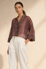 Mao Tencel Shirt in Burgundy – Μπλούζα με Mao Γιακά & Ιδιαίτερα Κουμπιά Χαρακτηριστικά Προϊόντος Σύνθεση: 95% Tencel – 5% lycra Ύφασμα: Λεπτό, σταθερό Tencel Υφή: Απαλή και λεία, με ανάλαφρη αίσθηση Γραμμή: Άνετη – relaxed fit Μέγεθος: One Size – καλύπτει από Small έως Extra Large Μανίκια: Φαρδιά, τρουακάρ  Οδηγίες Φροντίδας Για τη διατήρηση της υφής, των χρωμάτων και των ιδιαίτερων διακοσμητικών λεπτομερειών του Tencel, προτείνεται ήπια φροντίδα. 30°C – Πλύσιμο σε κρύο νερό, σε πρόγραμμα για ευαίσθητα, εφόσον το επιτρέπει η ετικέτα. Ήπιο στύψιμο ή χωρίς στύψιμο, για την προστασία του υφάσματος και των διακοσμητικών κορδονιών. ⊠ Όχι στεγνωτήριο. □ Φυσικό στέγνωμα στη σκιά, μακριά από άμεση ηλιακή ακτινοβολία. Πλύσιμο από την ανάποδη πλευρά, κατά προτίμηση μέσα σε ειδική θήκη προστασίας. Αποφύγετε την έντονη τριβή και το τράβηγμα των διακοσμητικών κόμπων.