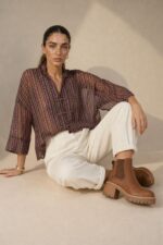 Mao Tencel Shirt in Burgundy – Μπλούζα με Mao Γιακά & Ιδιαίτερα Κουμπιά Χαρακτηριστικά Προϊόντος Σύνθεση: 95% Tencel – 5% lycra Ύφασμα: Λεπτό, σταθερό Tencel Υφή: Απαλή και λεία, με ανάλαφρη αίσθηση Γραμμή: Άνετη – relaxed fit Μέγεθος: One Size – καλύπτει από Small έως Extra Large Μανίκια: Φαρδιά, τρουακάρ  Οδηγίες Φροντίδας Για τη διατήρηση της υφής, των χρωμάτων και των ιδιαίτερων διακοσμητικών λεπτομερειών του Tencel, προτείνεται ήπια φροντίδα. 30°C – Πλύσιμο σε κρύο νερό, σε πρόγραμμα για ευαίσθητα, εφόσον το επιτρέπει η ετικέτα. Ήπιο στύψιμο ή χωρίς στύψιμο, για την προστασία του υφάσματος και των διακοσμητικών κορδονιών. ⊠ Όχι στεγνωτήριο. □ Φυσικό στέγνωμα στη σκιά, μακριά από άμεση ηλιακή ακτινοβολία. Πλύσιμο από την ανάποδη πλευρά, κατά προτίμηση μέσα σε ειδική θήκη προστασίας. Αποφύγετε την έντονη τριβή και το τράβηγμα των διακοσμητικών κόμπων.