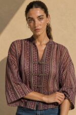Mao Tencel Shirt in Burgundy – Μπλούζα με Mao Γιακά & Ιδιαίτερα Κουμπιά Χαρακτηριστικά Προϊόντος Σύνθεση: 95% Tencel – 5% lycra Ύφασμα: Λεπτό, σταθερό Tencel Υφή: Απαλή και λεία, με ανάλαφρη αίσθηση Γραμμή: Άνετη – relaxed fit Μέγεθος: One Size – καλύπτει από Small έως Extra Large Μανίκια: Φαρδιά, τρουακάρ  Οδηγίες Φροντίδας Για τη διατήρηση της υφής, των χρωμάτων και των ιδιαίτερων διακοσμητικών λεπτομερειών του Tencel, προτείνεται ήπια φροντίδα. 30°C – Πλύσιμο σε κρύο νερό, σε πρόγραμμα για ευαίσθητα, εφόσον το επιτρέπει η ετικέτα. Ήπιο στύψιμο ή χωρίς στύψιμο, για την προστασία του υφάσματος και των διακοσμητικών κορδονιών. ⊠ Όχι στεγνωτήριο. □ Φυσικό στέγνωμα στη σκιά, μακριά από άμεση ηλιακή ακτινοβολία. Πλύσιμο από την ανάποδη πλευρά, κατά προτίμηση μέσα σε ειδική θήκη προστασίας. Αποφύγετε την έντονη τριβή και το τράβηγμα των διακοσμητικών κόμπων.