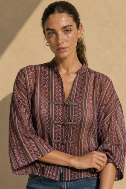 Mao Tencel Shirt in Burgundy – Μπλούζα με Mao Γιακά & Ιδιαίτερα Κουμπιά Χαρακτηριστικά Προϊόντος Σύνθεση: 95% Tencel – 5% lycra Ύφασμα: Λεπτό, σταθερό Tencel Υφή: Απαλή και λεία, με ανάλαφρη αίσθηση Γραμμή: Άνετη – relaxed fit Μέγεθος: One Size – καλύπτει από Small έως Extra Large Μανίκια: Φαρδιά, τρουακάρ  Οδηγίες Φροντίδας Για τη διατήρηση της υφής, των χρωμάτων και των ιδιαίτερων διακοσμητικών λεπτομερειών του Tencel, προτείνεται ήπια φροντίδα. 30°C – Πλύσιμο σε κρύο νερό, σε πρόγραμμα για ευαίσθητα, εφόσον το επιτρέπει η ετικέτα. Ήπιο στύψιμο ή χωρίς στύψιμο, για την προστασία του υφάσματος και των διακοσμητικών κορδονιών. ⊠ Όχι στεγνωτήριο. □ Φυσικό στέγνωμα στη σκιά, μακριά από άμεση ηλιακή ακτινοβολία. Πλύσιμο από την ανάποδη πλευρά, κατά προτίμηση μέσα σε ειδική θήκη προστασίας. Αποφύγετε την έντονη τριβή και το τράβηγμα των διακοσμητικών κόμπων.